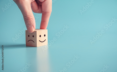 Obraz na plátně Close up customer hand choose smiley face and sad face icon on wood cube, Service rating, satisfaction concept, copy space