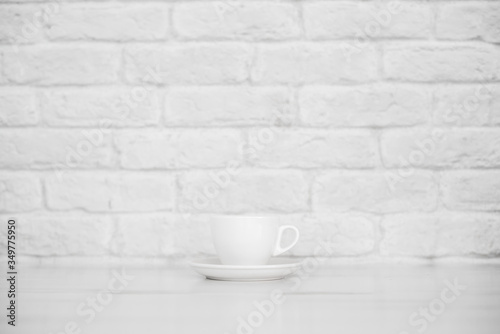 white espresso mug on a white table against a white brick wall