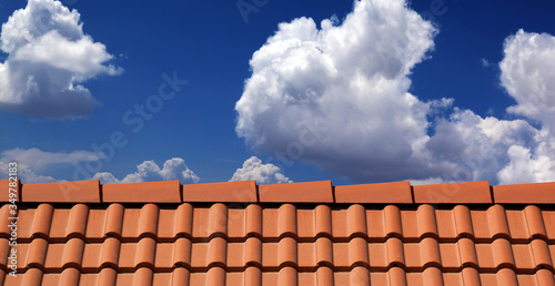 Roof tiles against blue sky with clouds