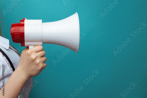 Doctor's advice and healthcare announcement concept with white lab coat holding a megaphone isolated on blue background with space for text.