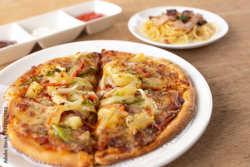 Pizza with spaghetti, tomato sauce, chilli sauce, mayonnaise sauce on wooden table