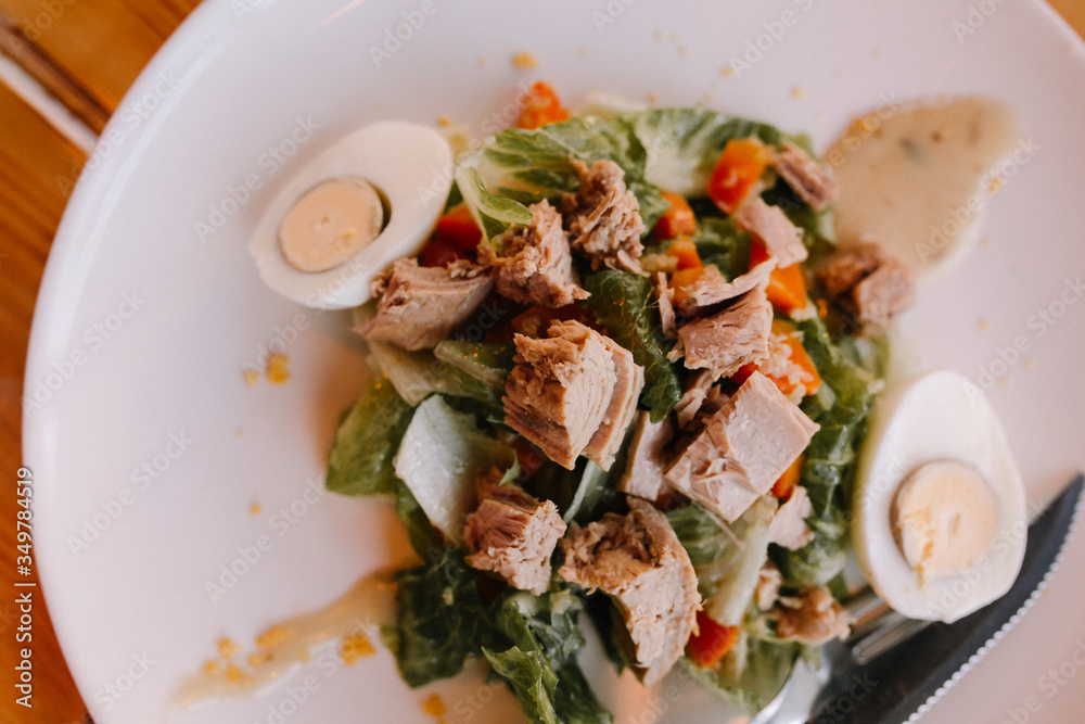 Salad on a white plate of green leaves with canned tuna, with an egg. Dietary food. Proper nutrition. Salad on a white plate of green leaves with canned tuna, with an egg. Dietary food. Proper nutrition.