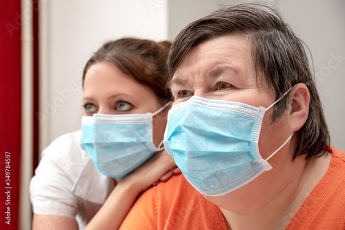 Mentally disabled woman and nurse or caretaker wearing a surgical mask, covid-19 or corona photo