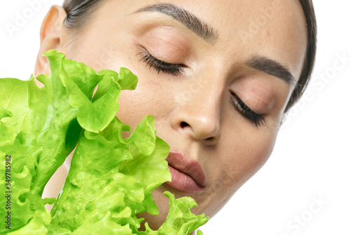 portrait of a girl with clean skin without makeup with a leaf of green salad