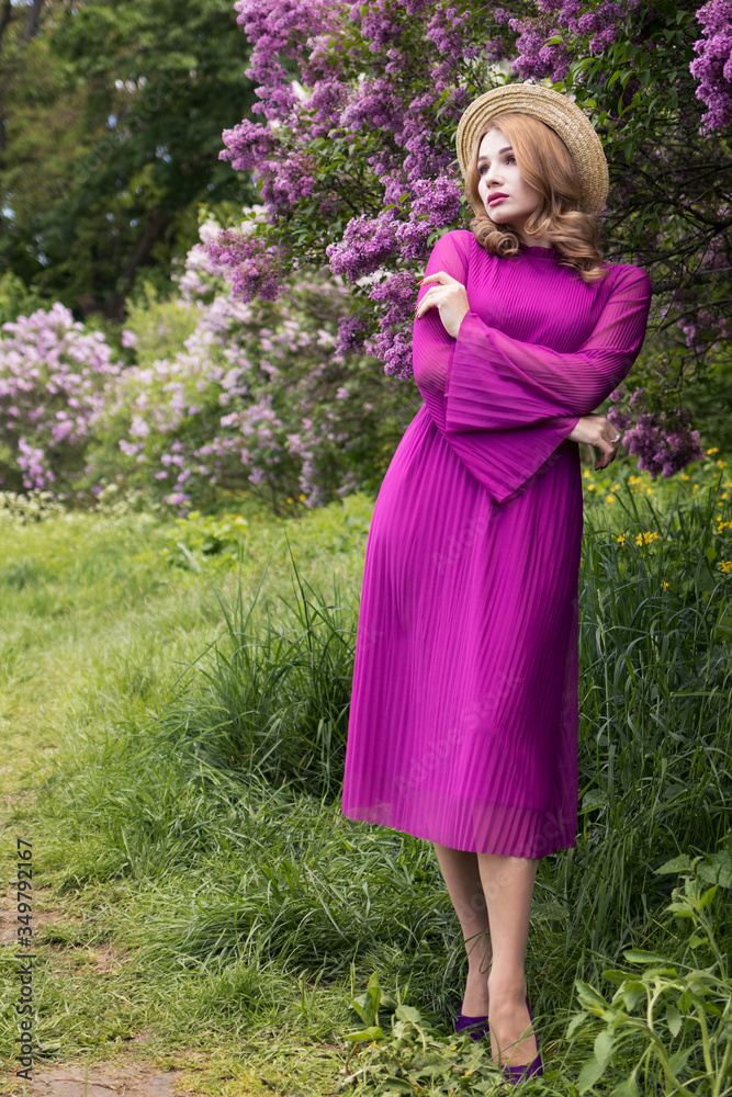 Beautiful woman in a hat among the bushes of blossoming lilac, vertical photo Beautiful woman in a hat among the bushes of blossoming lilac, vertical photo