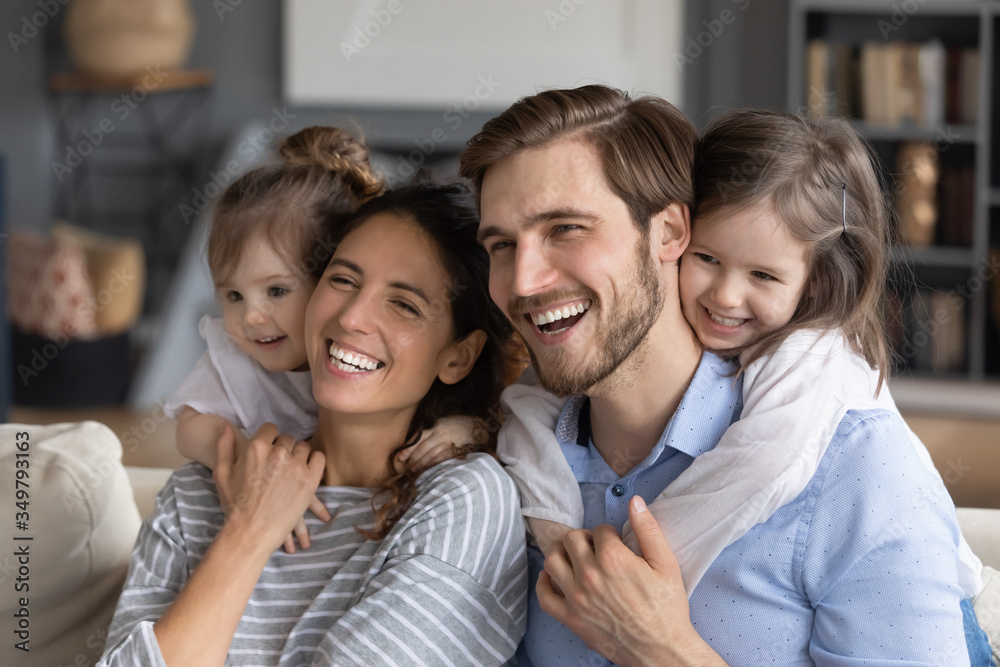 Overjoyed young Caucasian family with little daughters hug cuddle enjoy weekend at home together, smiling happy parents with small girls kids have fun playing, show love and unity, bonding concept Overjoyed young Caucasian family with little daughters hug cuddle enjoy weekend at home together, smiling happy parents with small girls kids have fun playing, show love and unity, bonding concept