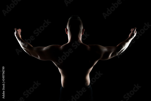 Healthy muscular young man with his arms stretched out isolated on black background