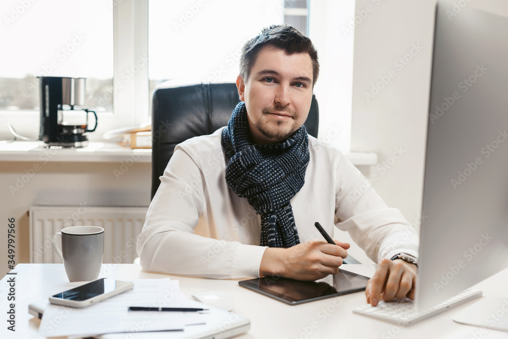 Young handsome freelancer, architect or designer working on a new creative project on a computer in an office using a graphics tablet. Middle-aged man inspired by ideas and creativity.