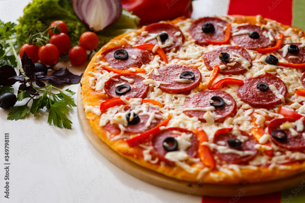 Hot italian pizza on a table with vegetables Hot italian pizza on a table with vegetables
