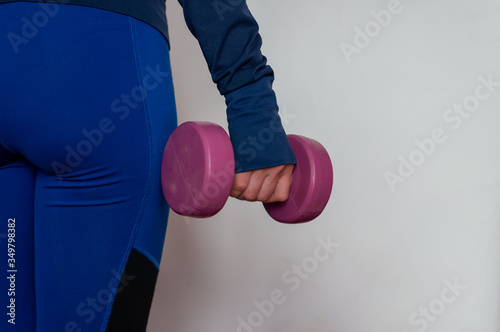 Young woman working out at home with pink weights, on white background. sport & keeping fit.