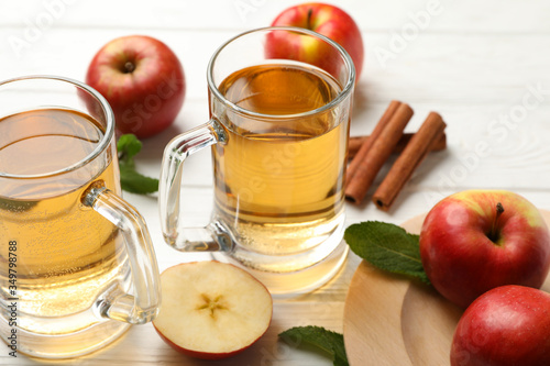 Composition with cider, cinnamon and apples on white wooden background