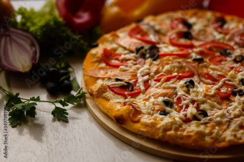 Hot italian pizza on a table with vegetables