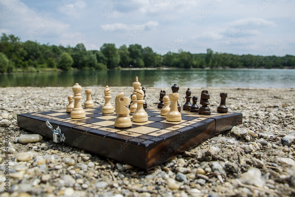 Playing chess near the lake Štrkovisko in Senec, Slovakia. Chessboard on a stone beach with a great landscape