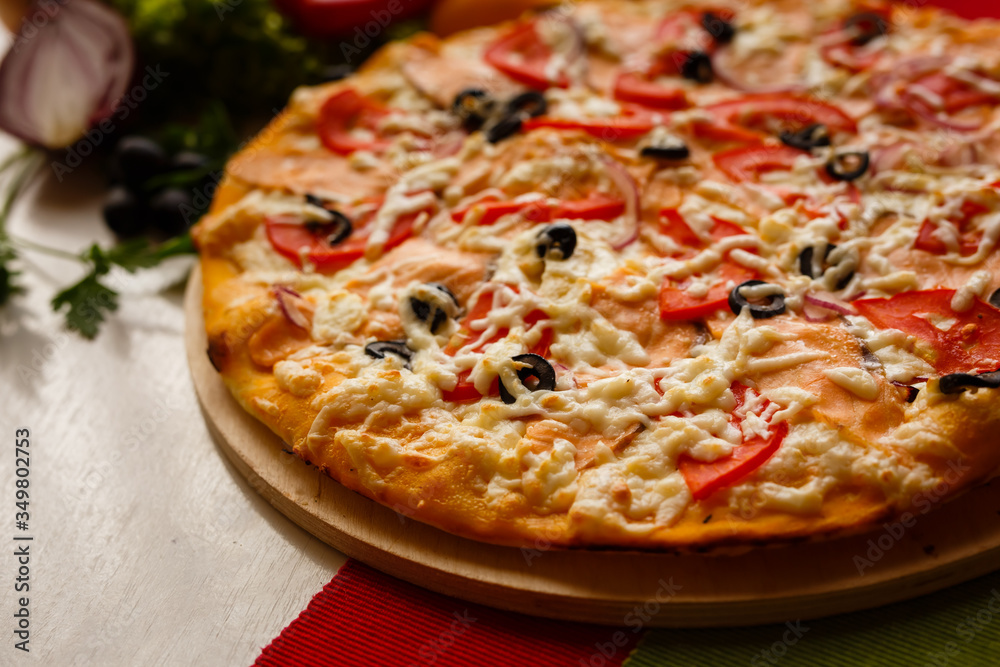 Hot italian pizza on a table with vegetables Hot italian pizza on a table with vegetables