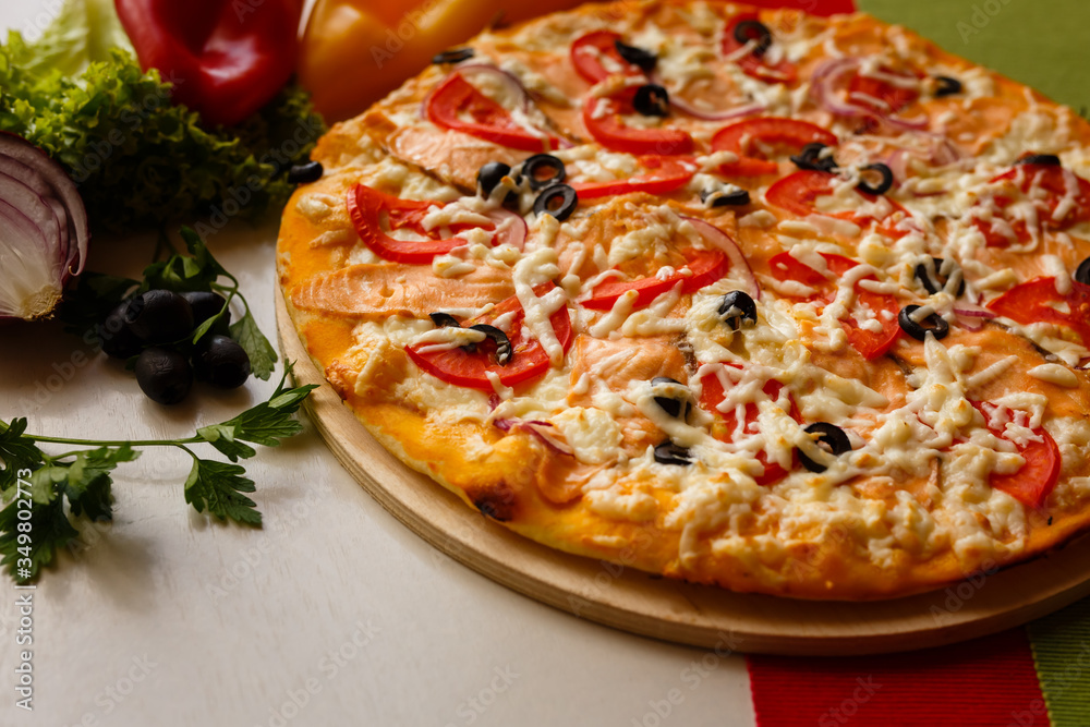 Hot italian pizza on a table with vegetables Hot italian pizza on a table with vegetables