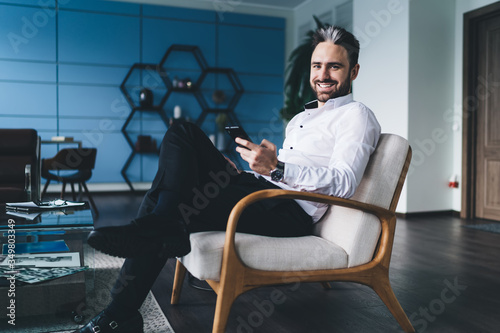Joyful businessman chatting on smartphone in office