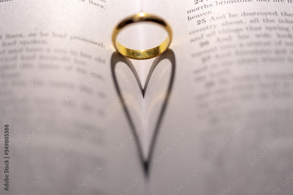 Fototapeta premium A wedding Ring on the bible with shadow of heart shape on the page