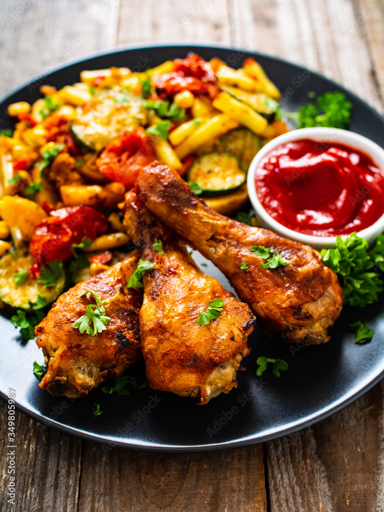 Barbecue chicken drumsticks with vegetables on wooden table
