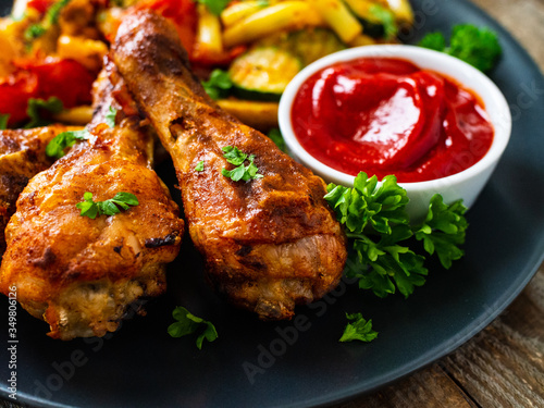 Barbecue chicken drumsticks with vegetables on wooden table 