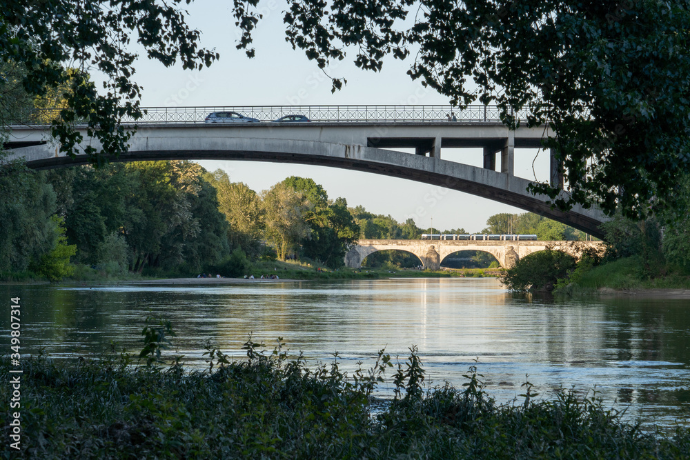 Tram and cars crossing bridges over Loire river in France.