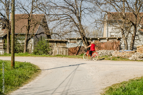 A lady in a red blouse on a bicycle 