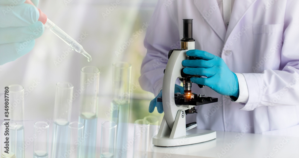 laboratory concept; scientist uses a microscope, with blurred of research activity in the laboratory laboratory concept; scientist uses a microscope, with blurred of research activity in the laboratory