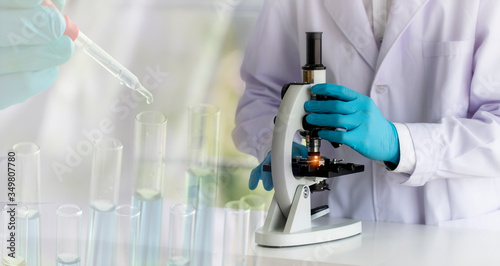 laboratory concept; scientist uses a microscope, with blurred of research activity in the laboratory