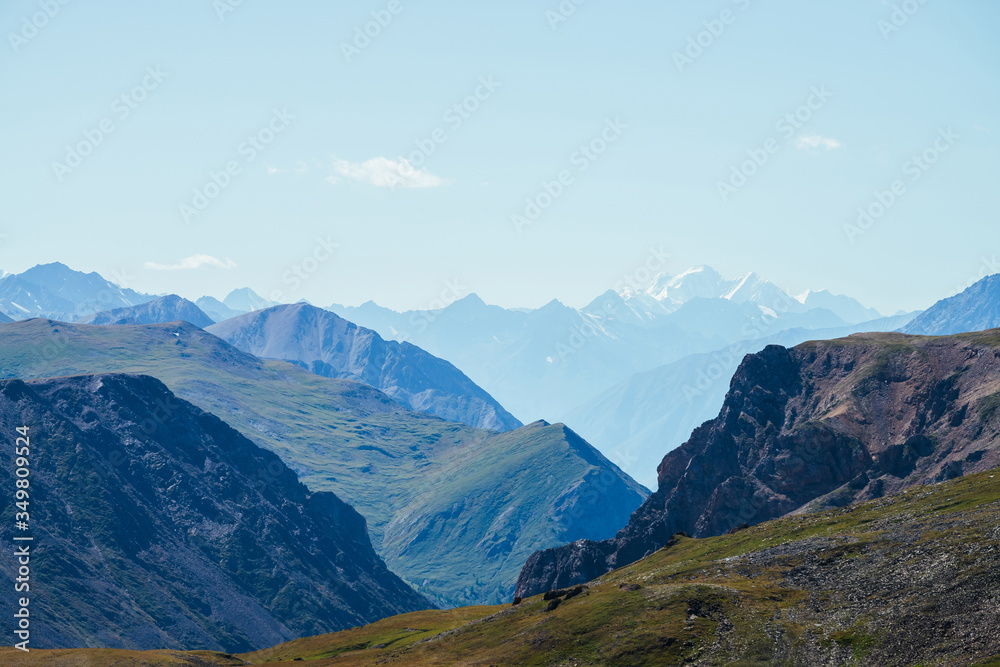 Awesome scenic view to great snowy mountains behind deep gorge. Wonderful mountain landscape with giant rockies and deep abyss. Highland scenery with huge glacier in distance. Big rocks and precipice.