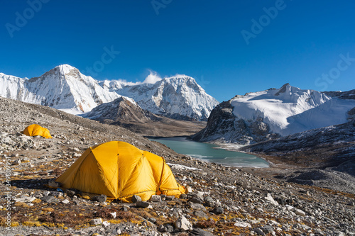 Yellow tents at Amphulapcha base camp surrounded by Himalaya mountains range in Everest region, Nepal photo