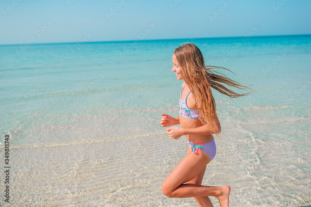 Adorable little girl have fun at tropical beach during vacation
