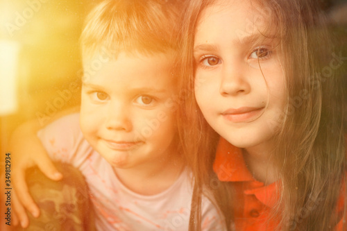 kids siblings boy and girl looks through the window during covid-19 quarantine. stay at home, let's all be well. flare