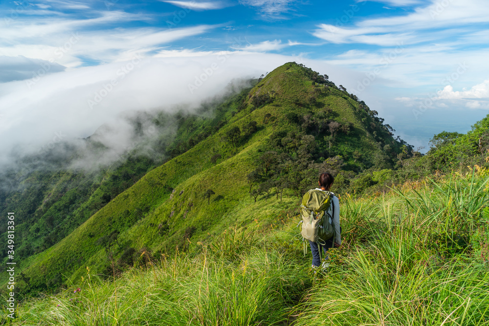 A woman trekker with backpack walking on ridge of Doi Luang Payao, summer in Thailand