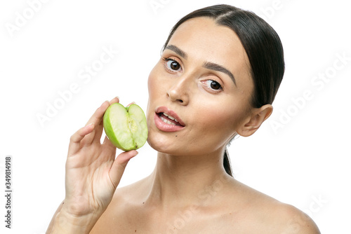 close-up portrait of a girl with clear skin holding a apple to her face, isolated on a white background