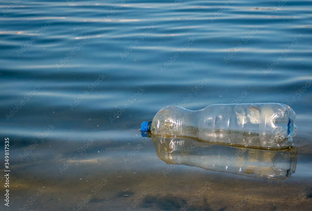 A PET plastic bottle floating on water of a lake in Bucharest, Romania. Plastic pollution environment concept. A PET plastic bottle floating on water of a lake in Bucharest, Romania. Plastic pollution environment concept.