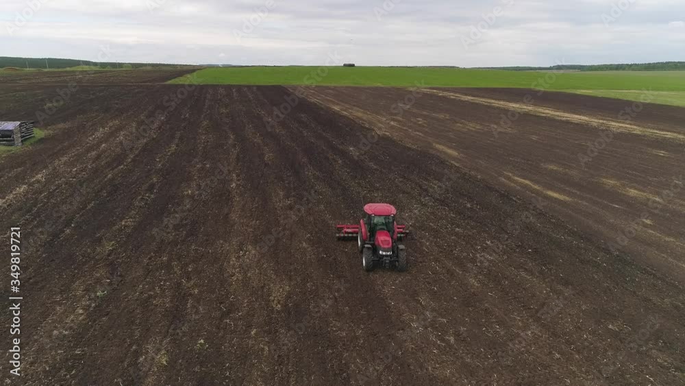 Aerial view of tractor cultivates farm field for sowing. Farm tractor with rotary harrow plow preparing land for sowing. Cultivation of farmland by disc harrows.
Aerial view of tractor cultivates farm field for sowing. Farm tractor with rotary harrow plow preparing land for sowing. Cultivation of farmland by disc harrows.