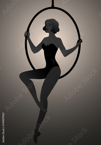 Backlit silhouette of woman trapeze artist sitting on a hoop suspended in the air