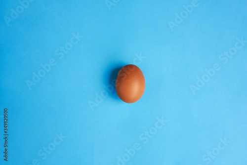 Brown egg on blue background. Real farm egg. Natural healthy food and organic farming concept © Maletina