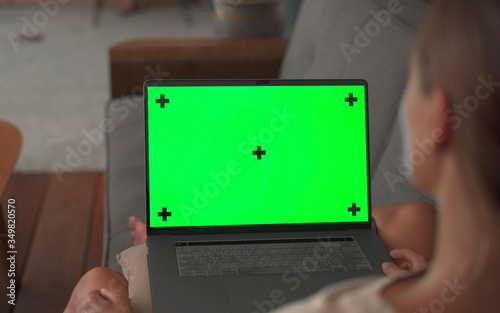Mock Up green Screen laptop holding by woman sitting on couch in living room