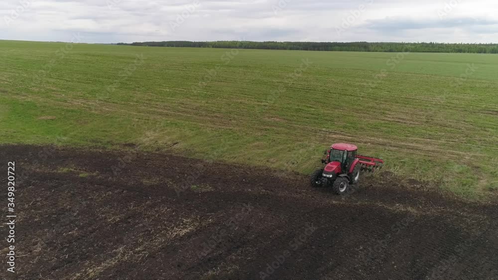 03. Aerial view of tractor cultivates farm field for sowing. Farm tractor with rotary harrow plow preparing land for sowing. Cultivation of farmland by disc harrows.
03. Aerial view of tractor cultivates farm field for sowing. Farm tractor with rotary harrow plow preparing land for sowing. Cultivation of farmland by disc harrows.