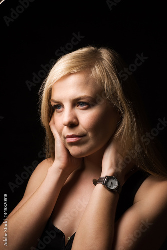 A beautiful young, businesslike blonde girl with a thoughtful look on a black background.