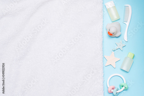 Baby's accessories (toys, hair brush, shampoo, lotion, towel) on blue background with copy space; top view, flat lay