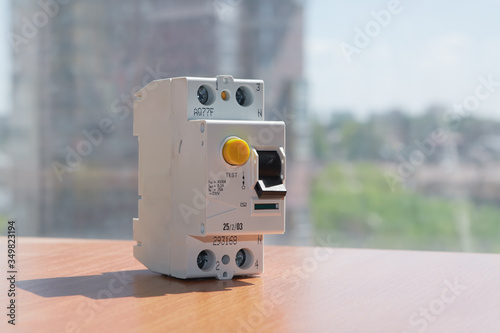 Residual current device on the table against the background of a residential building. A device for protecting human life and health from touching exposed electrical wires.