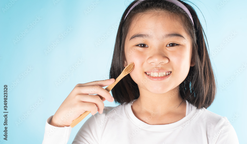An Asian child is holding a toothbrush.