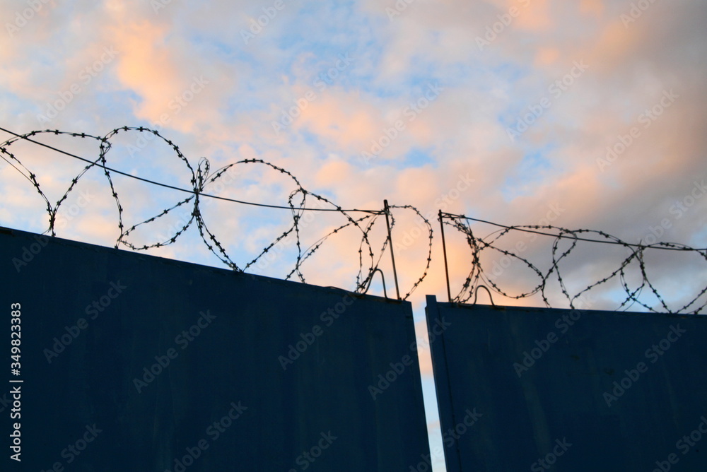 gates with barbed wire on a background of pink clouds gates with barbed wire on a background of pink clouds