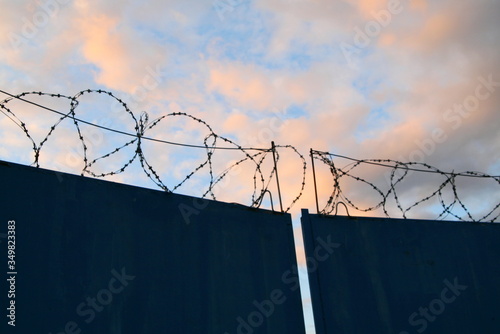 gates with barbed wire on a background of pink clouds