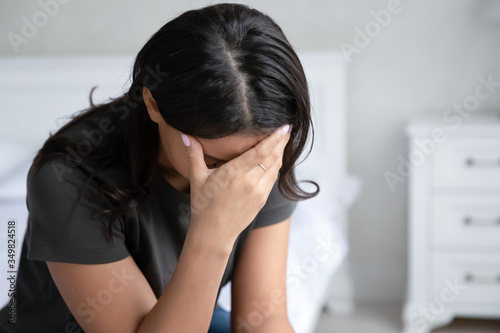 Close up view African mixed-race woman with drooping head sitting indoors feels despair due unplanned pregnancy hard decision about abortion, cheated wife and divorce break up, home violence concept