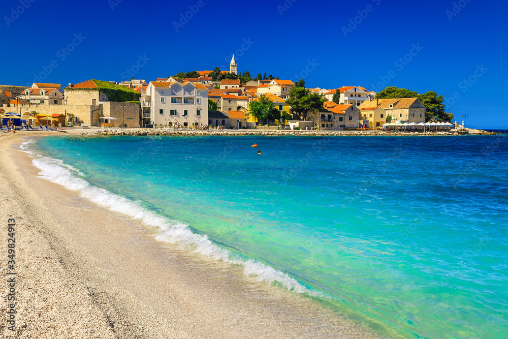 Sandy beach with waves and Primosten resort in background, Croatia