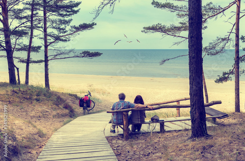 Happy couple of seniors are resting together with their dog, sandy beach of t...