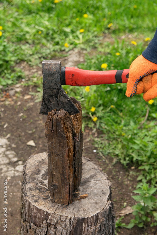 Hands hold an ax and chop wood on a stump Hands hold an ax and chop wood on a stump