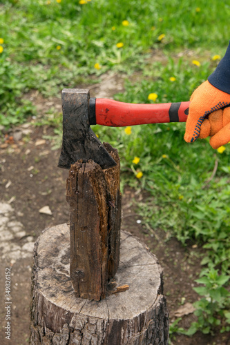 Hands hold an ax and chop wood on a stump